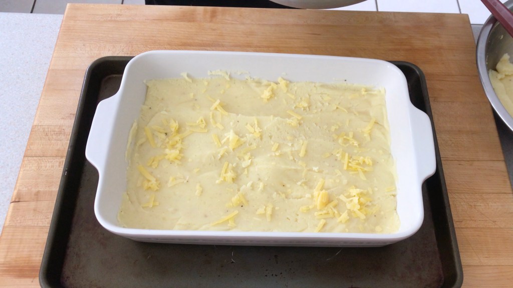 The bottom layer of the pie - potatoes with s light sprinkling of cheddar cheese.