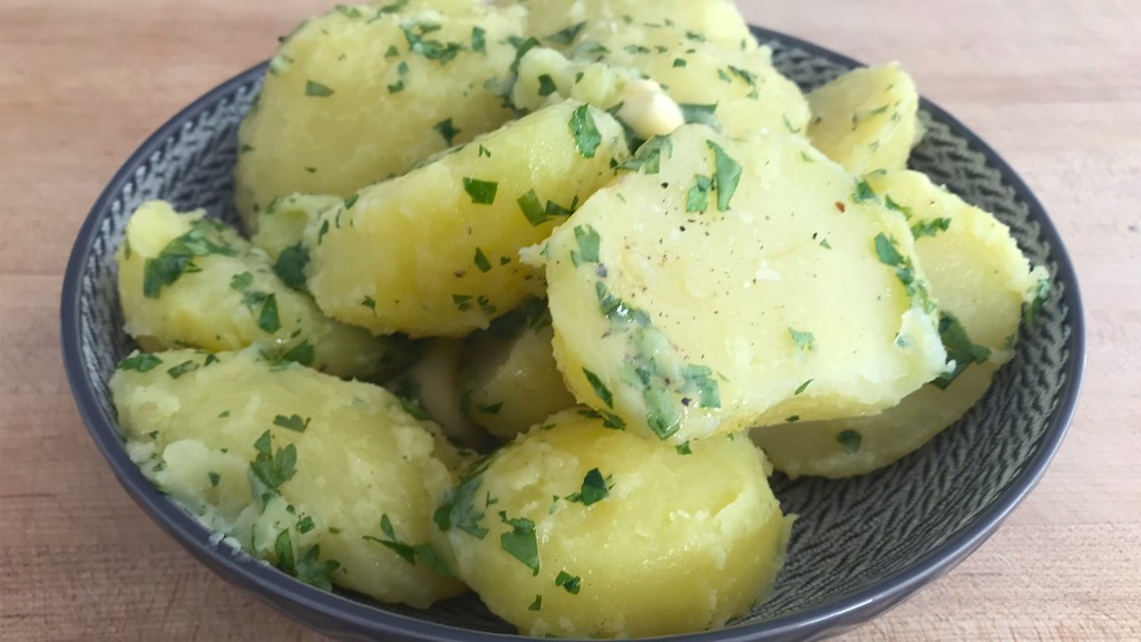 The steamed potatoes after tossing in salt, pepper, butter and parsley, in a serving bowl.