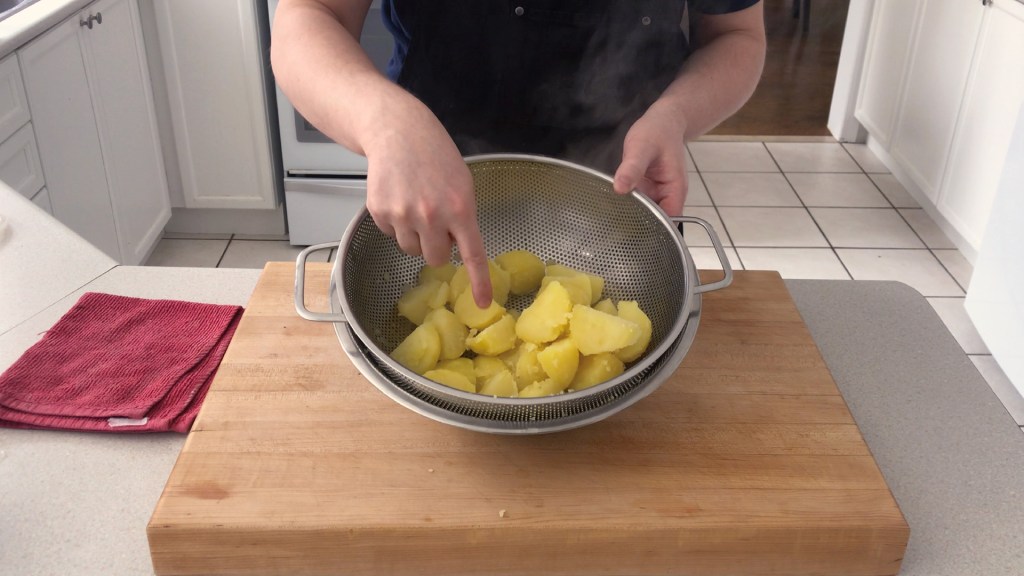 The potatoes after boiling and tossing gently in the colander. The edges are roughed up, but the potatoes are still intact.